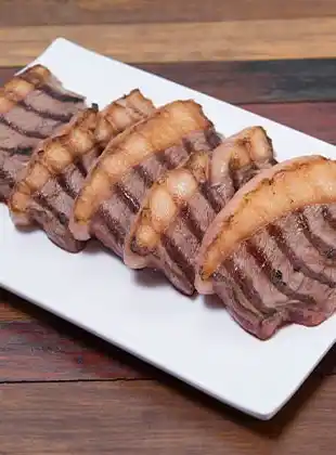 Fatias de carne grelhada em prato branco
